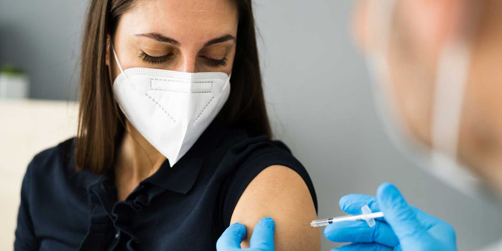 Women getting an injection with a face mask on