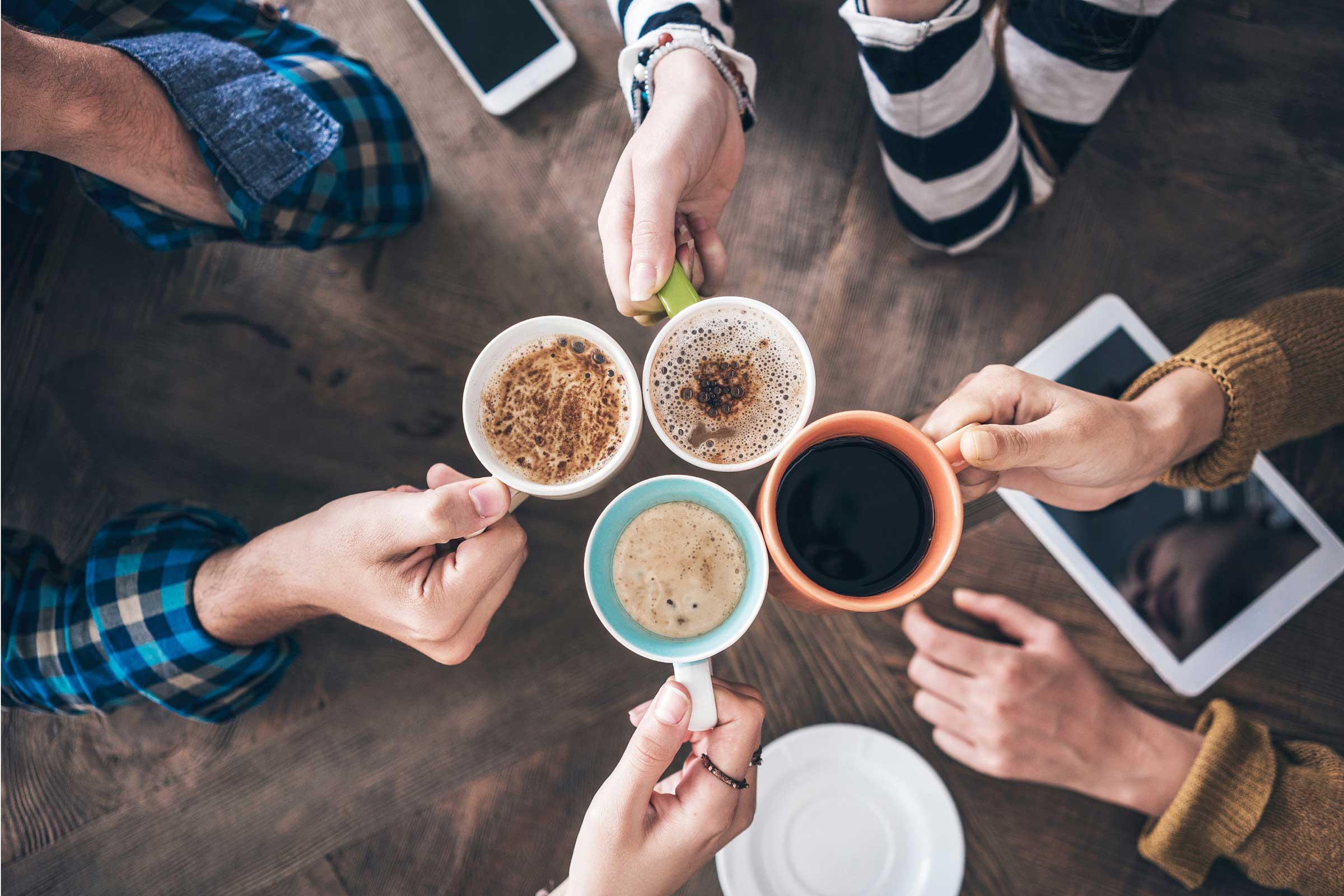Four people chinking mugs together