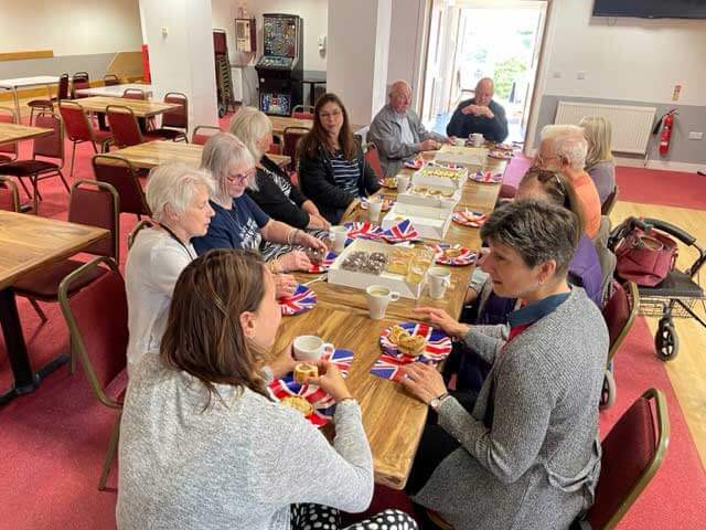 Group of people around a table having tea and cake
