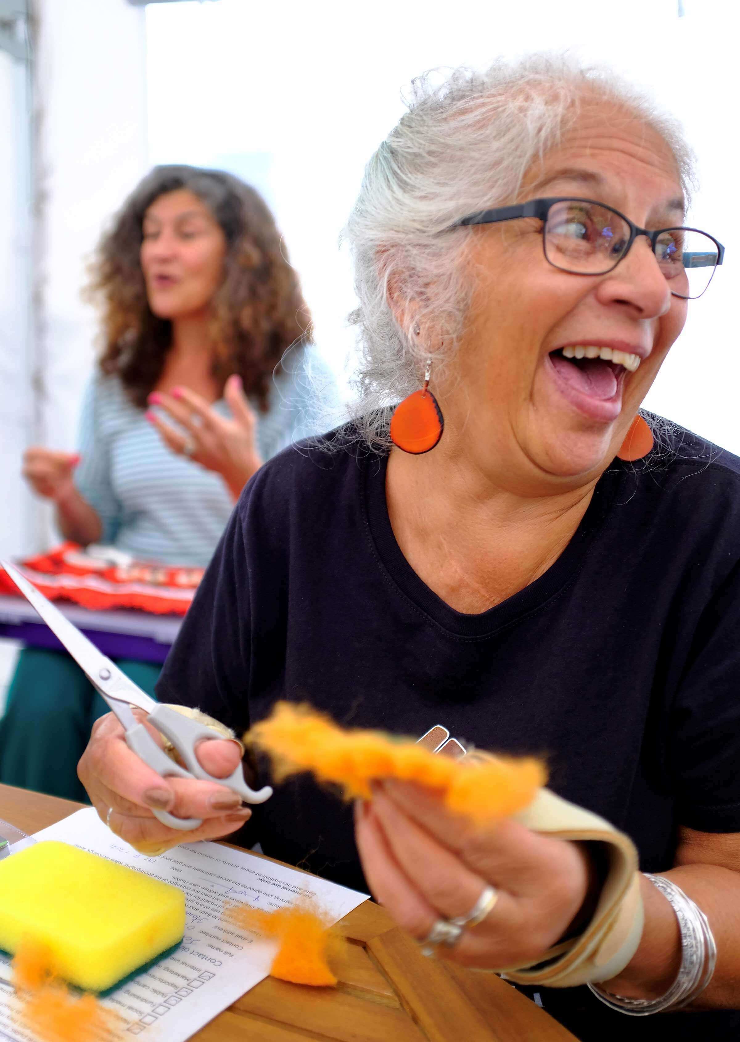 Woman laughing looking at someone off camera while doing crafts