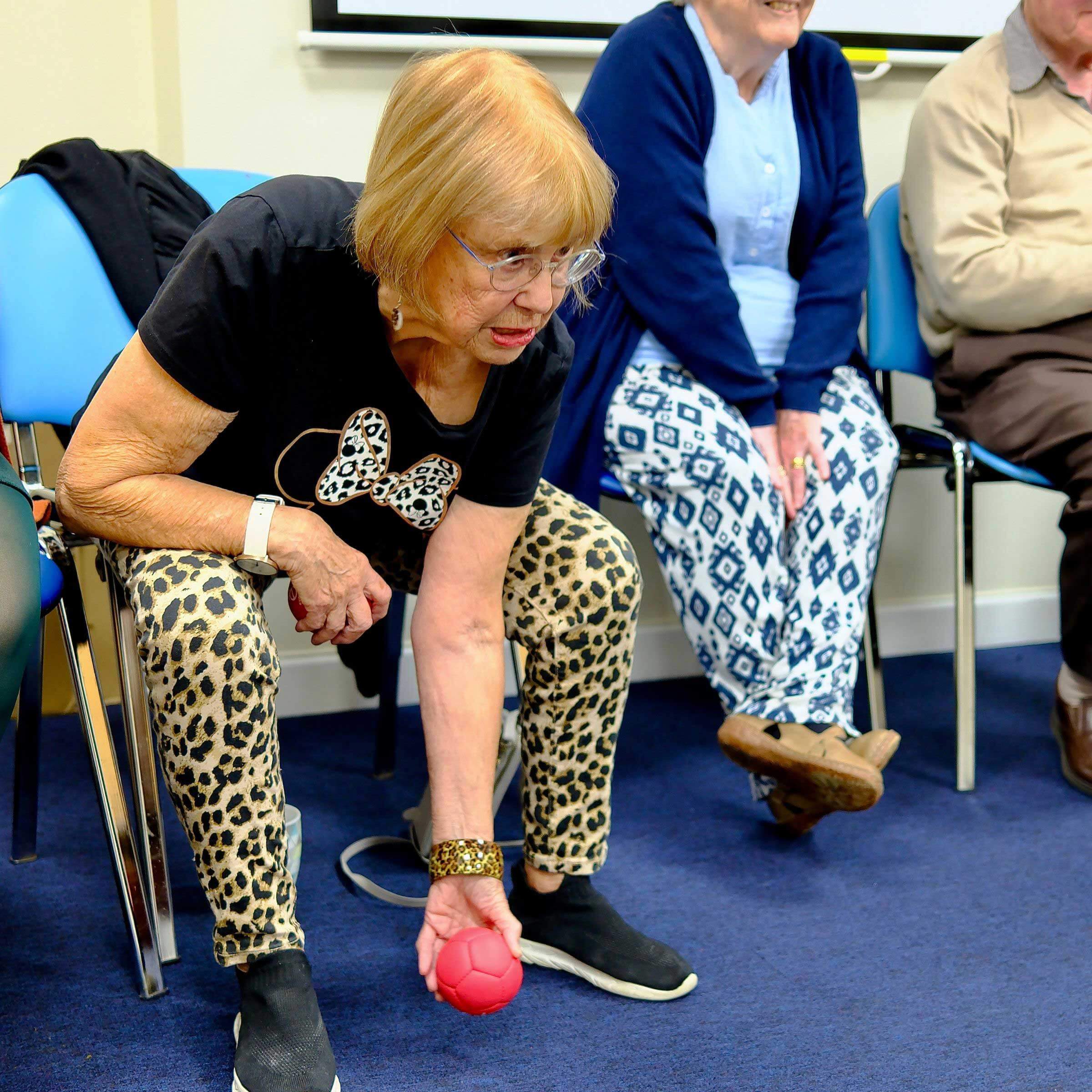 Woman sat down bent over about to roll a ball