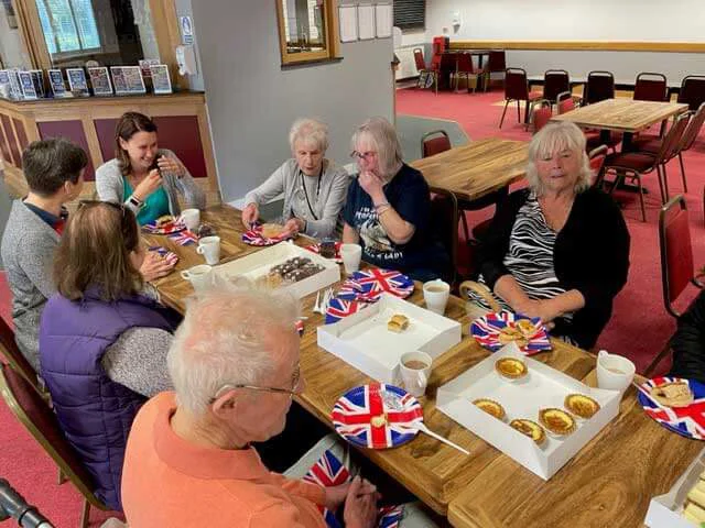 Group of people sat around a table eating cake