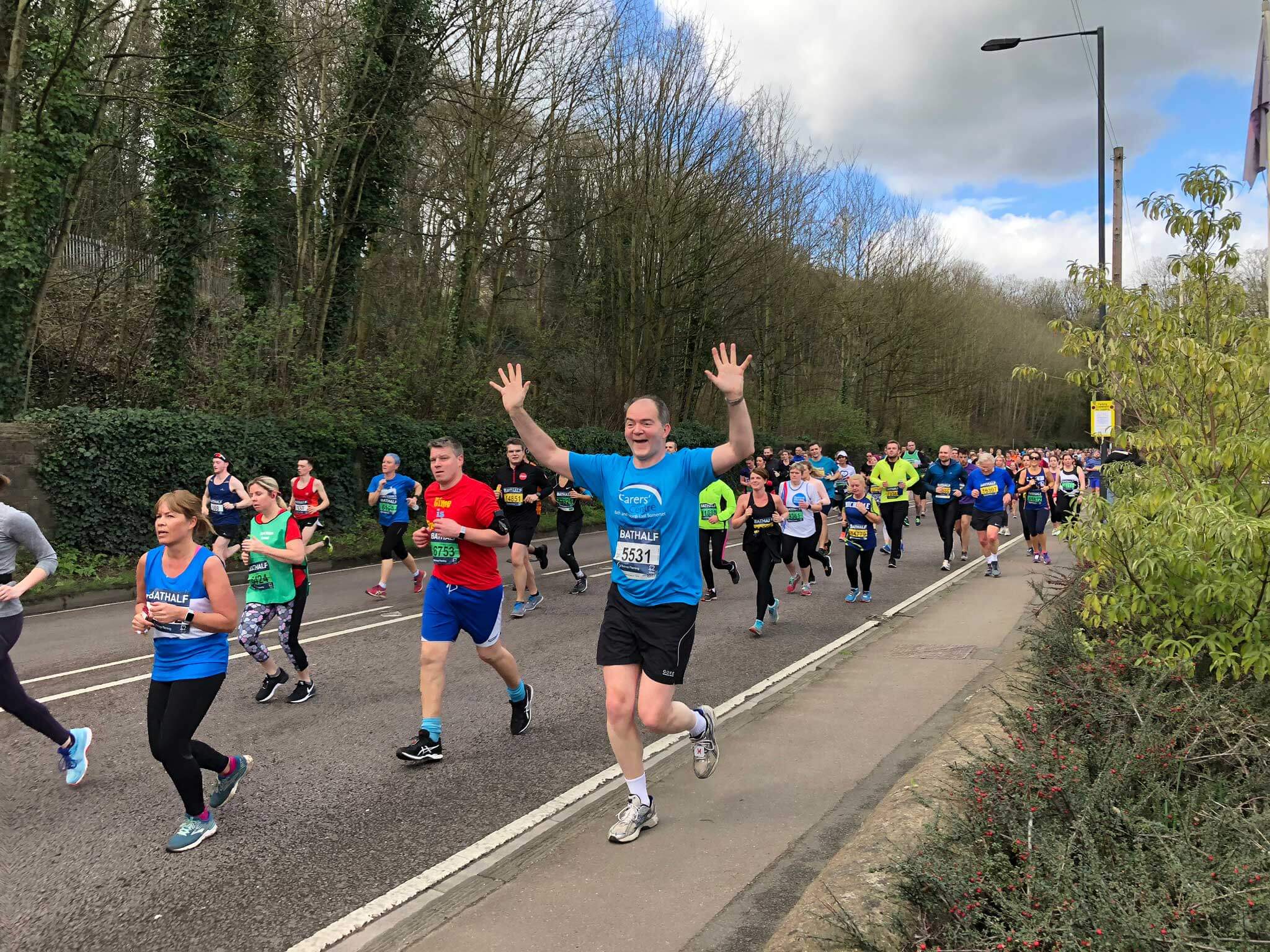 Man running in a Carers' Centre top with his hand up in the air