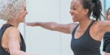 Two women wearing black tops stretch out their arms