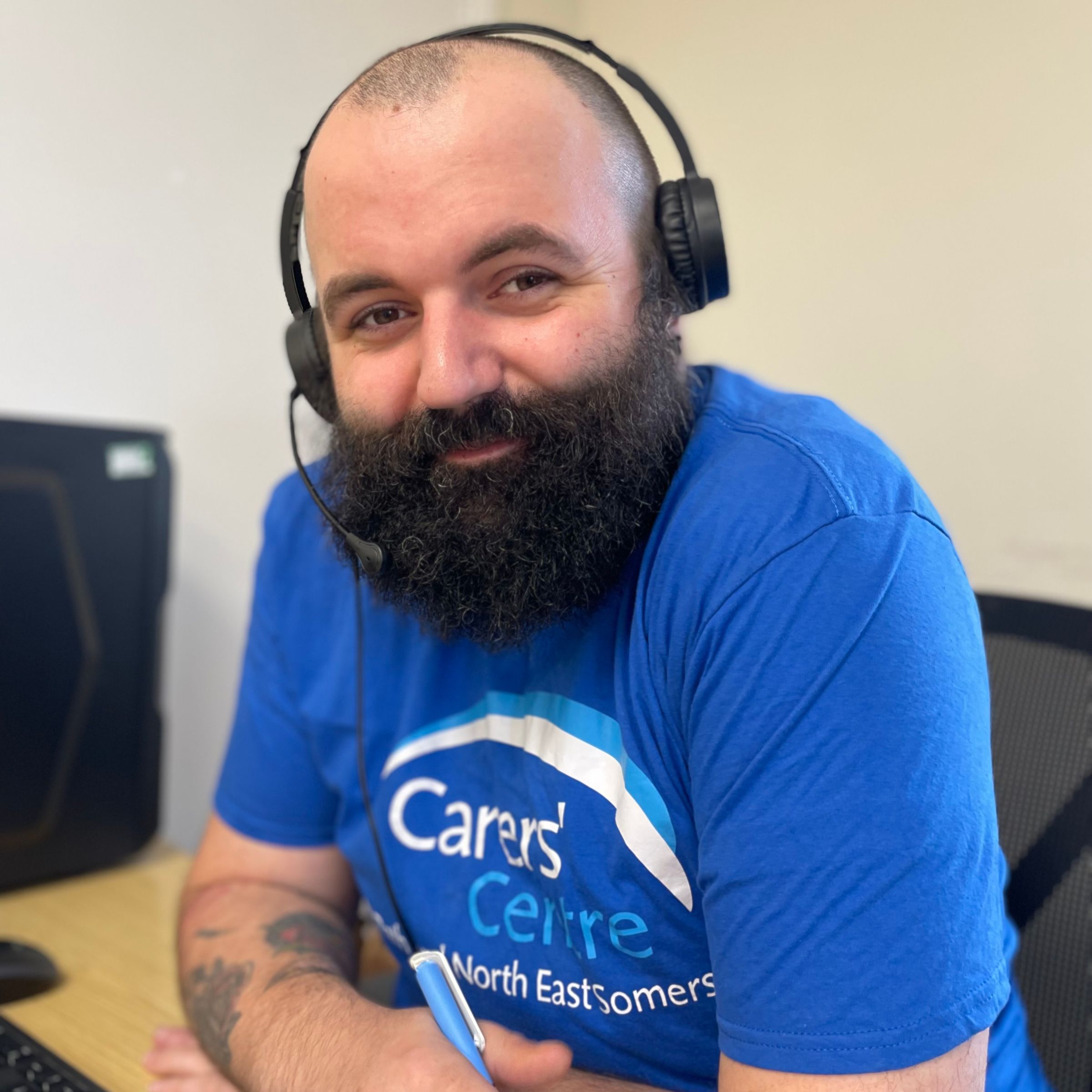 Image of Charlie wearing a blue Carer's Centre T shirt and a black headset. 