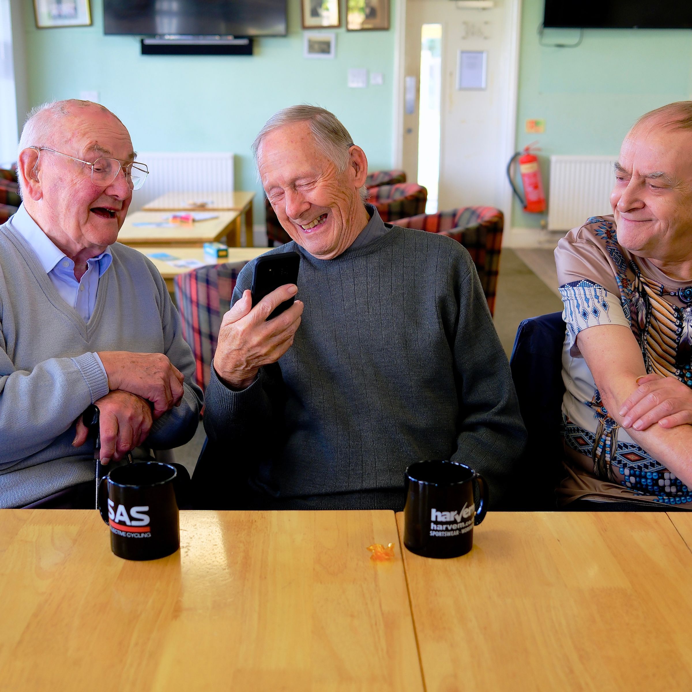 Three older men seated laughing at carer cafe