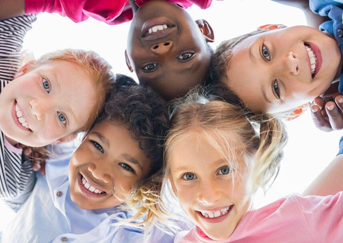 Group of child huddled over the camera smiling down