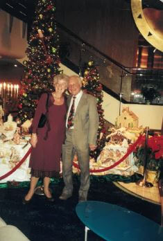 Couple stood together with Christmas trees in the background