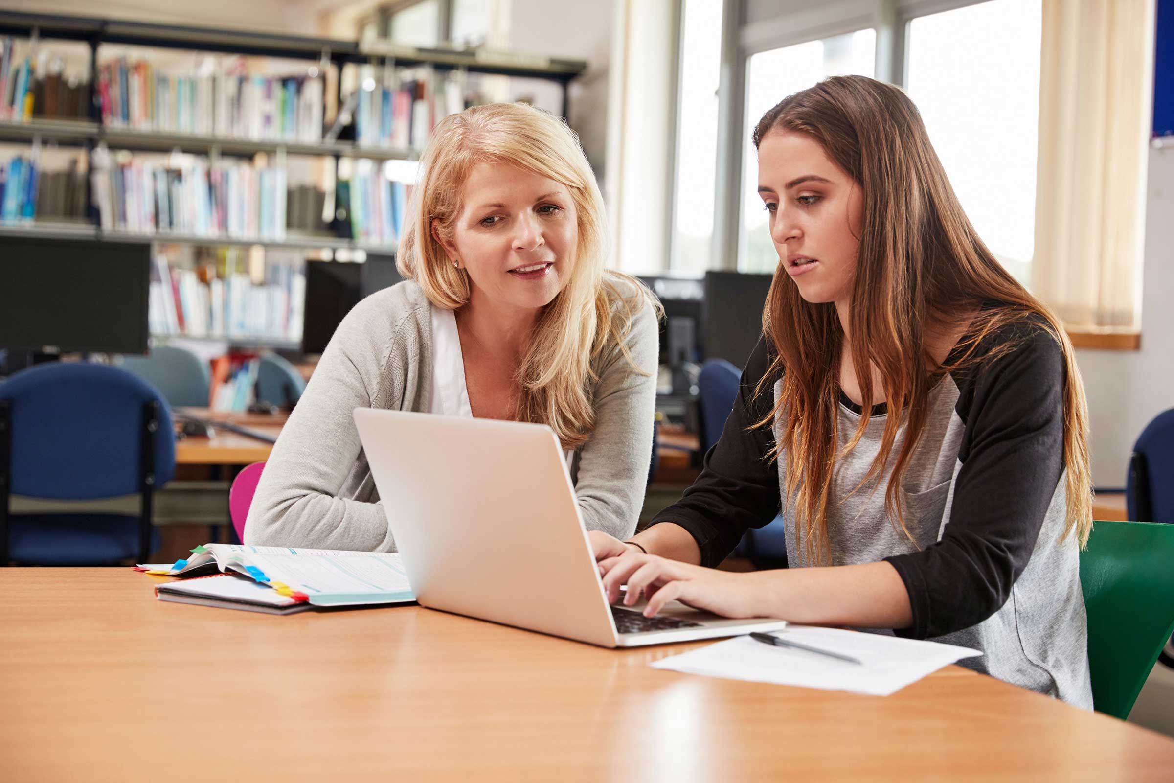 Young person on a laptop being supported by an adult