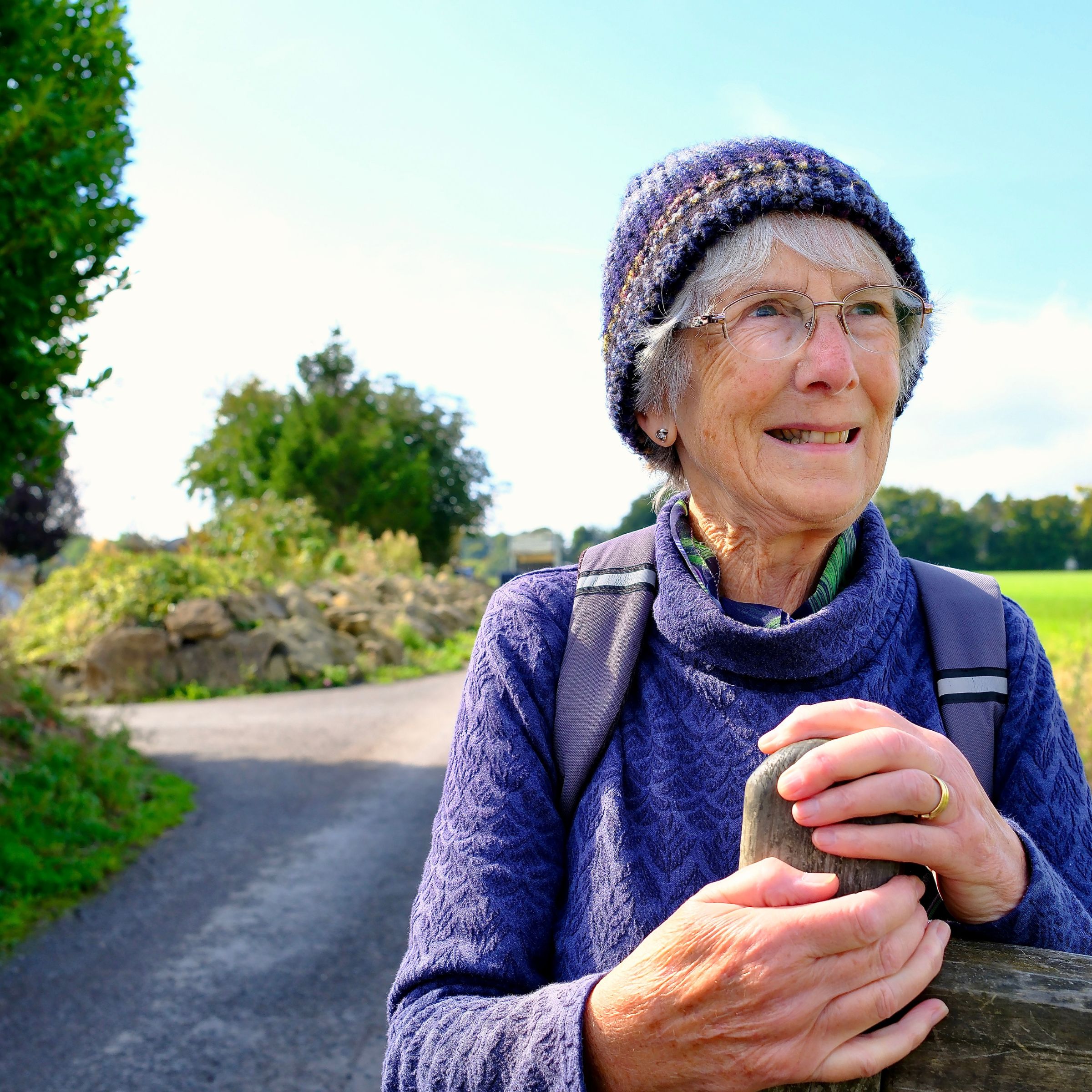 Older woman on hike smiling by open gate