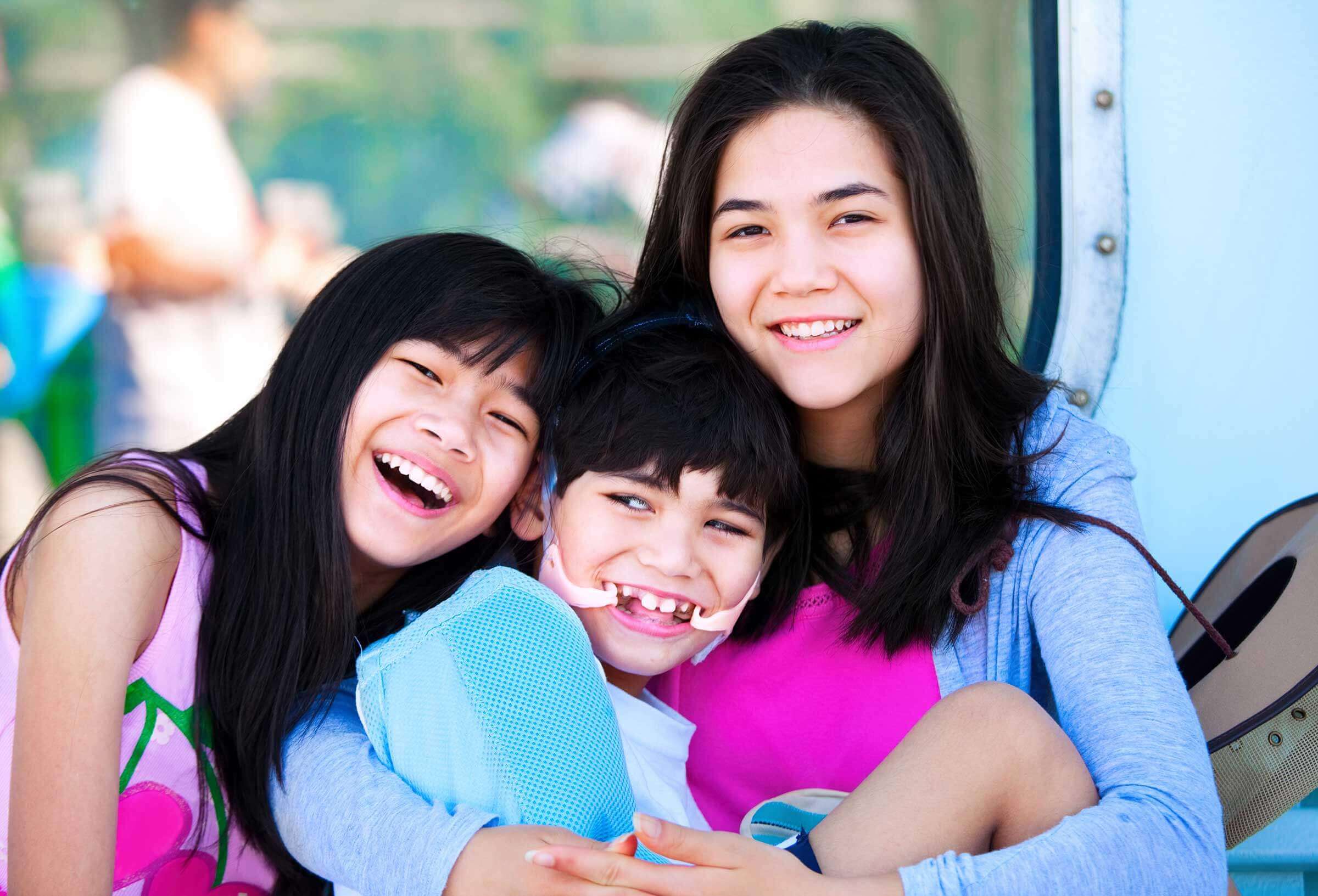 Two girls hugging their brother
