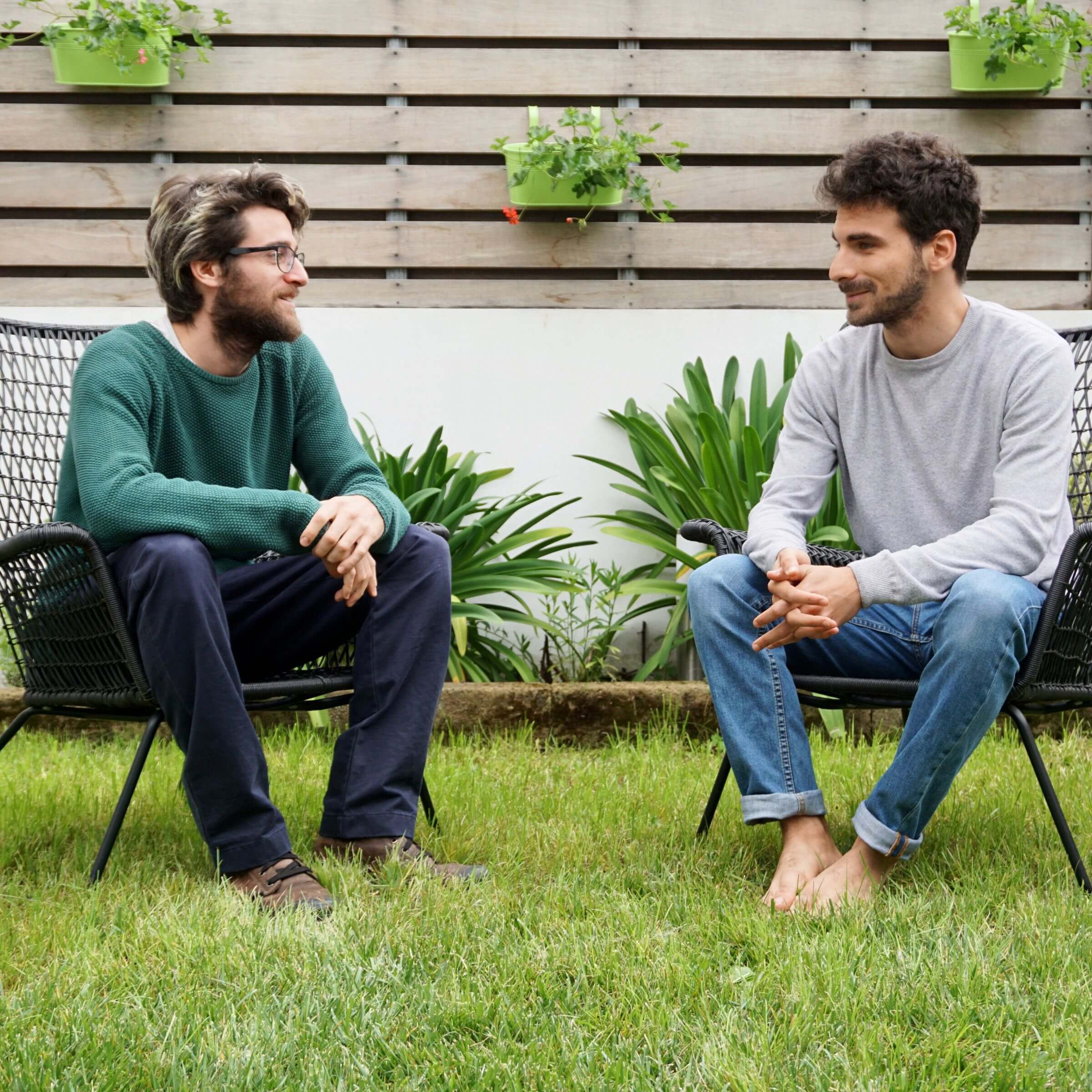 Two men sit next to each other in a garden