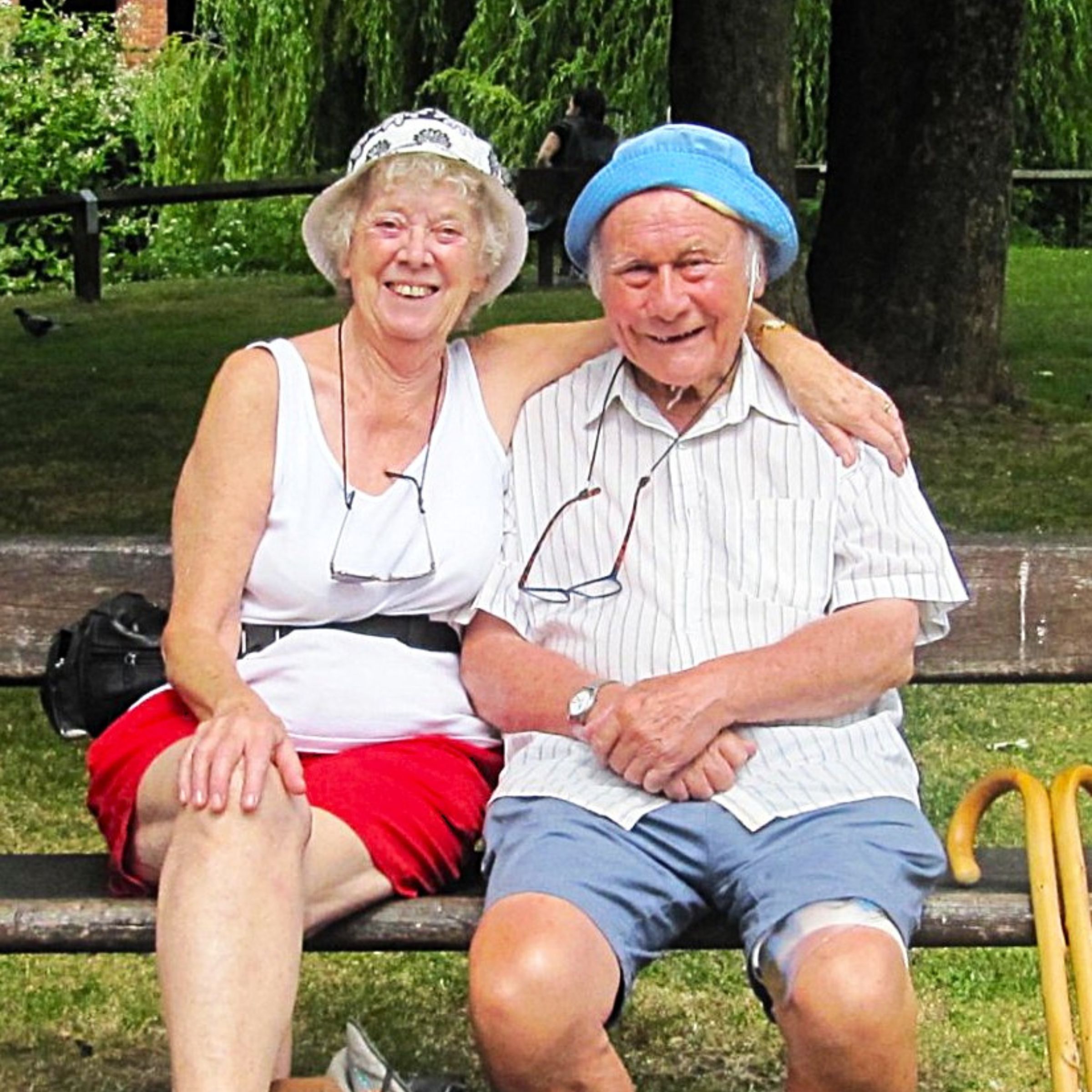 Lynda and Brian hugging on bench, in summer clothing