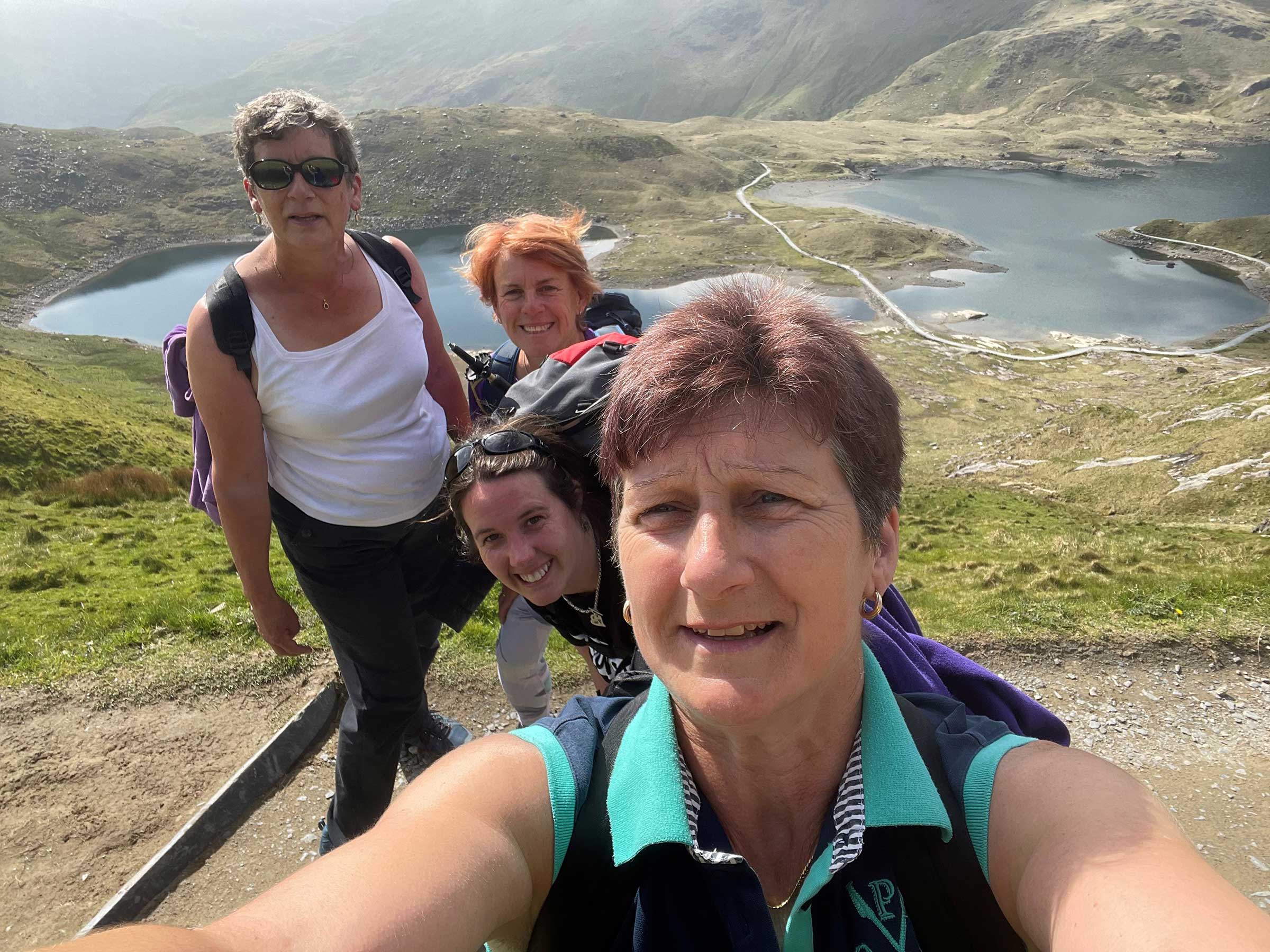 Sara taking a selfie with friends in the background smiling at the camera