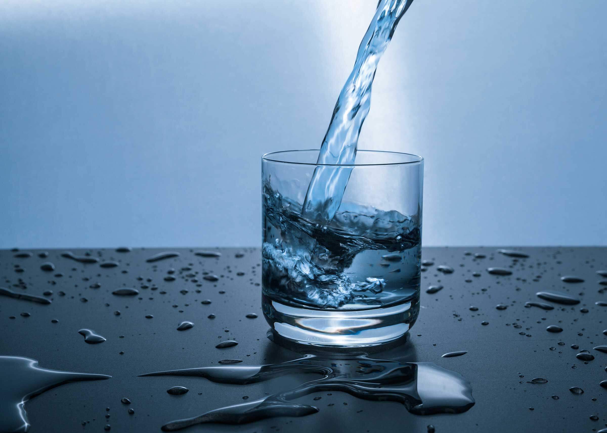 Glass of water with water being poured into glass