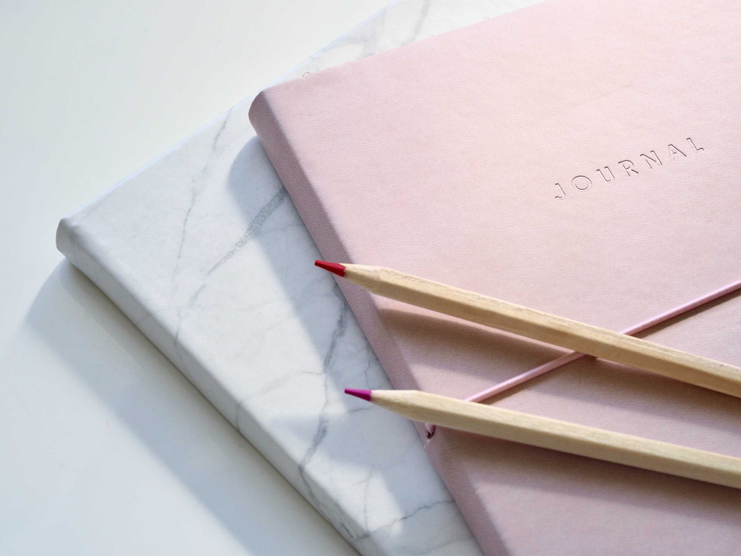 Two journal books with two pencils on top of the books