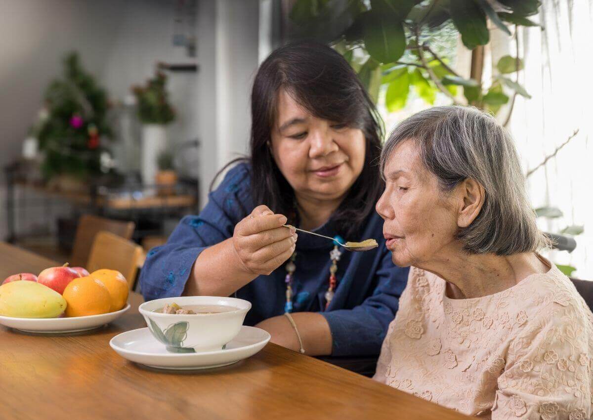 Chinese lady feeding and old chinese lady food sat at a table