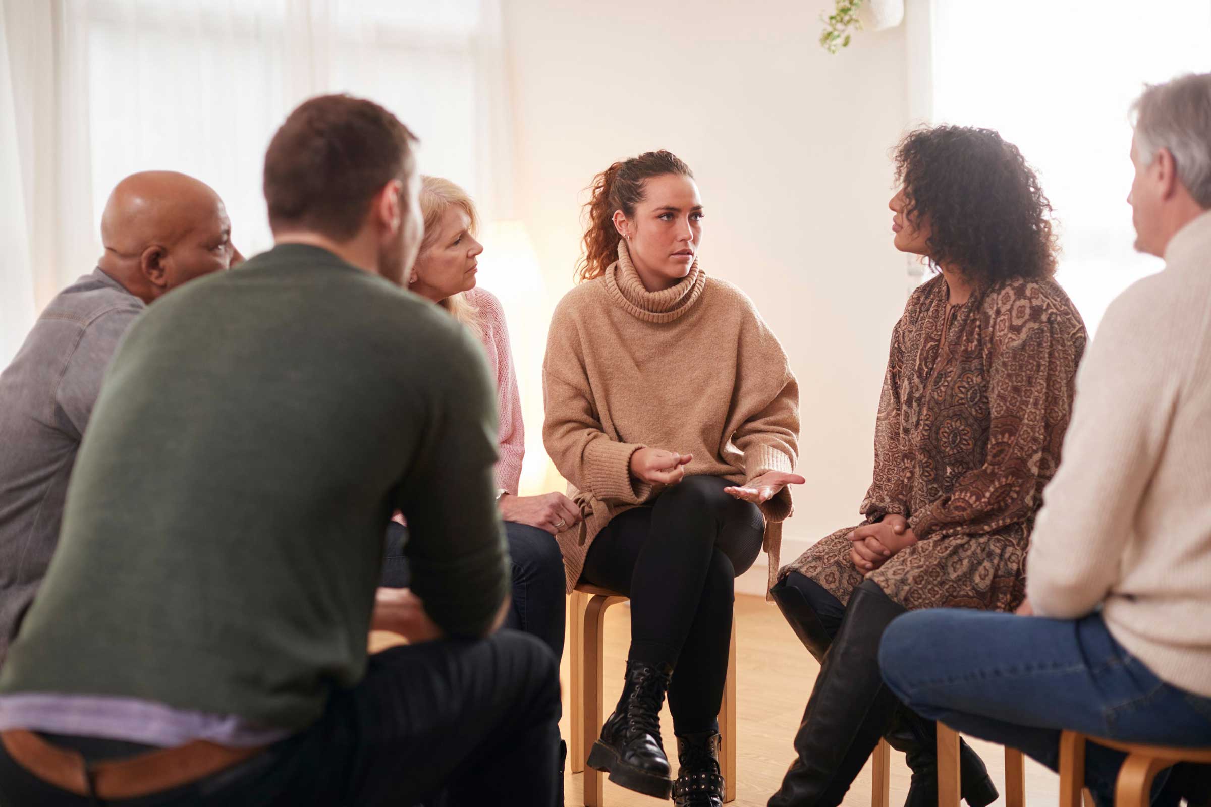 Group of people on stools with one lady speaking to the group