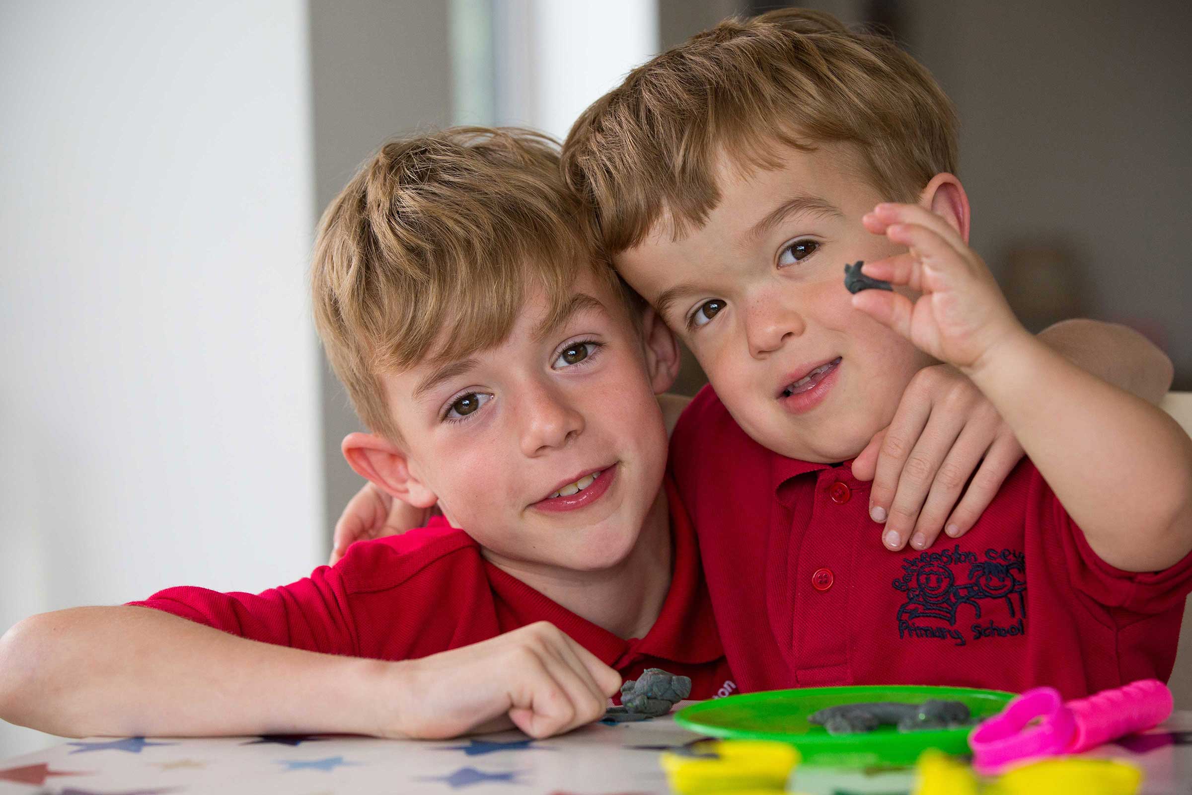 Young carer Charlie with his arm around his brother both looking at the camera