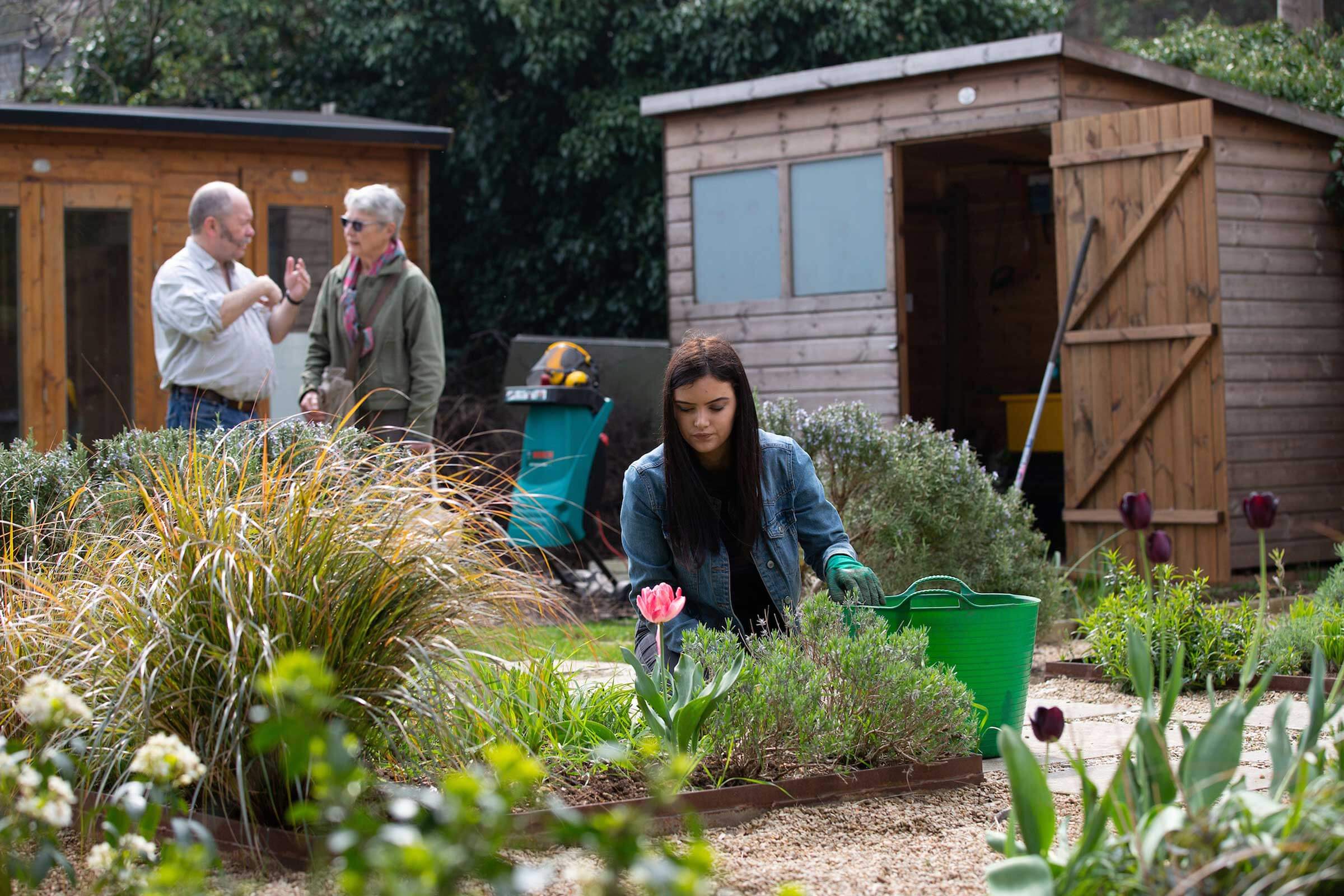 Girl gardening with people in the background talking