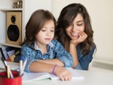 Image of a mum with long brown hair watching her child read a book