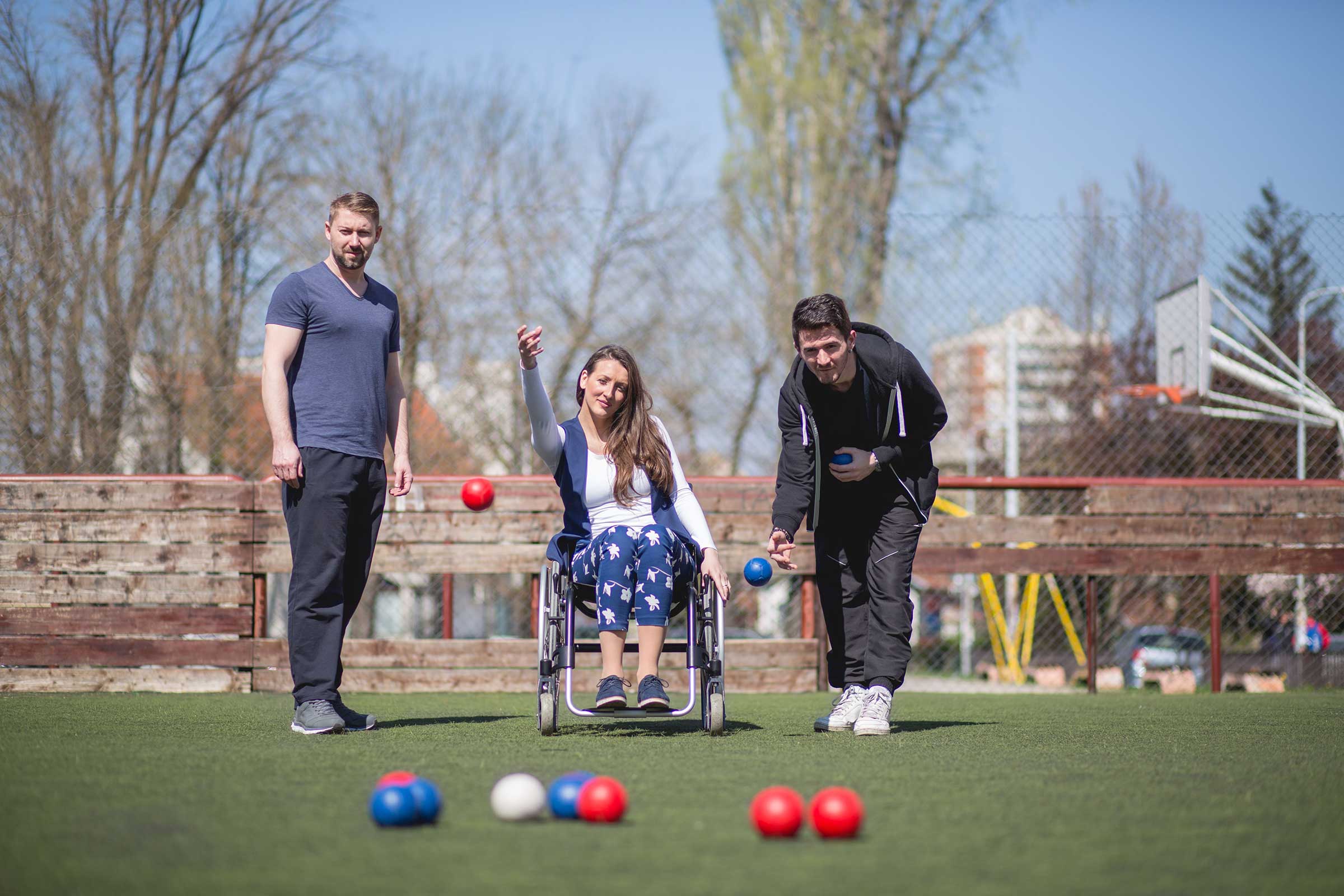 Two men and a women in a wheelchair playing bowls
