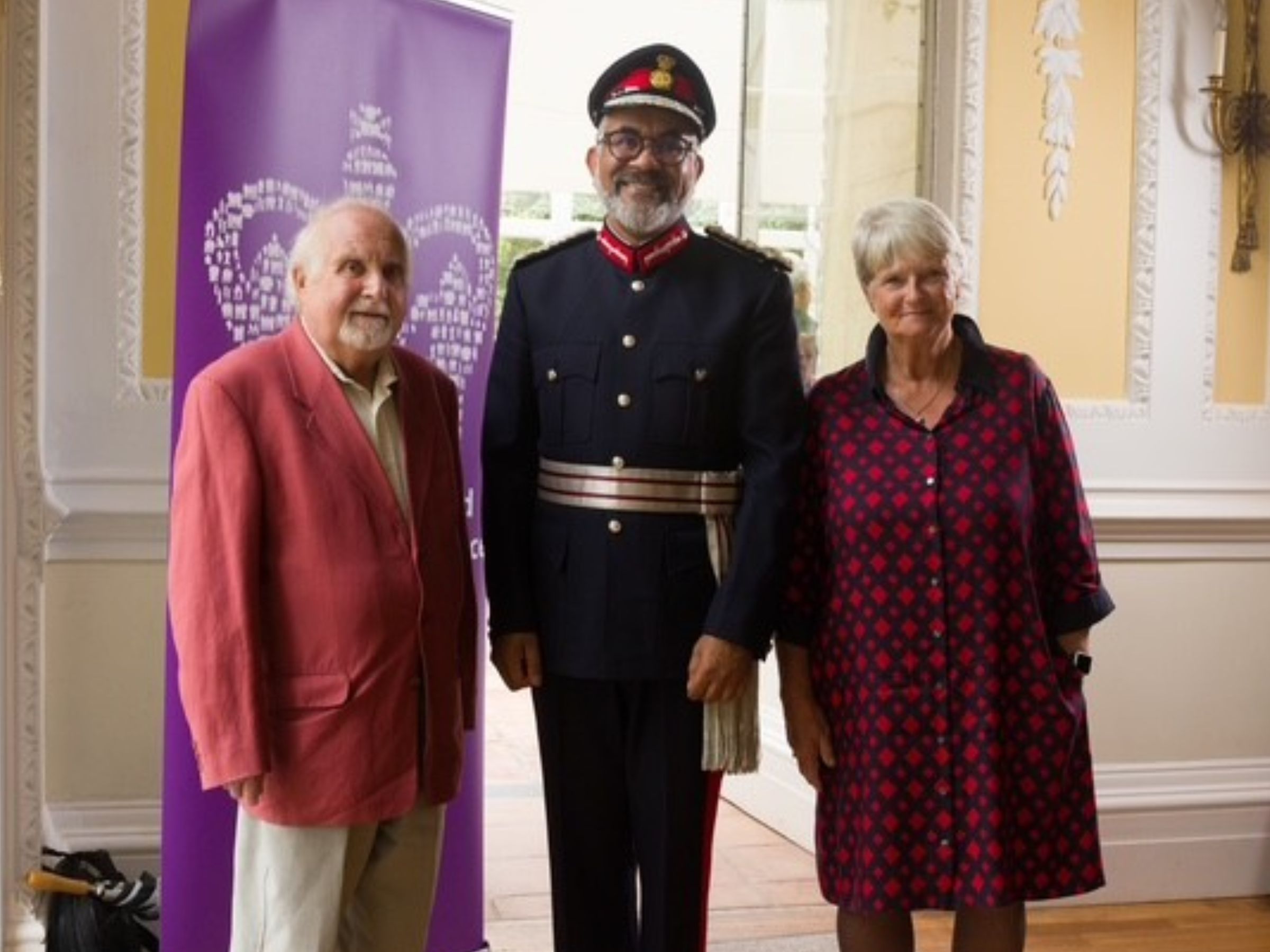 Lord-Lieutenant with volunteers Jenny and Lyndon standing in a grand event room 