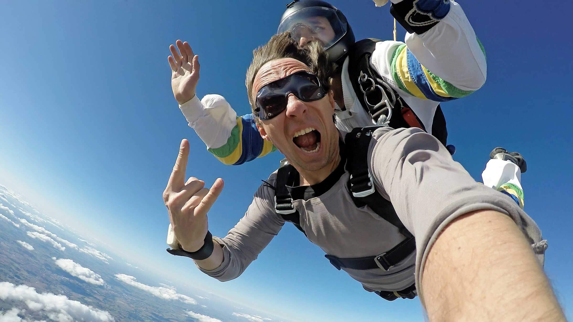 Man holding a phone taking a selfie of him skydiving