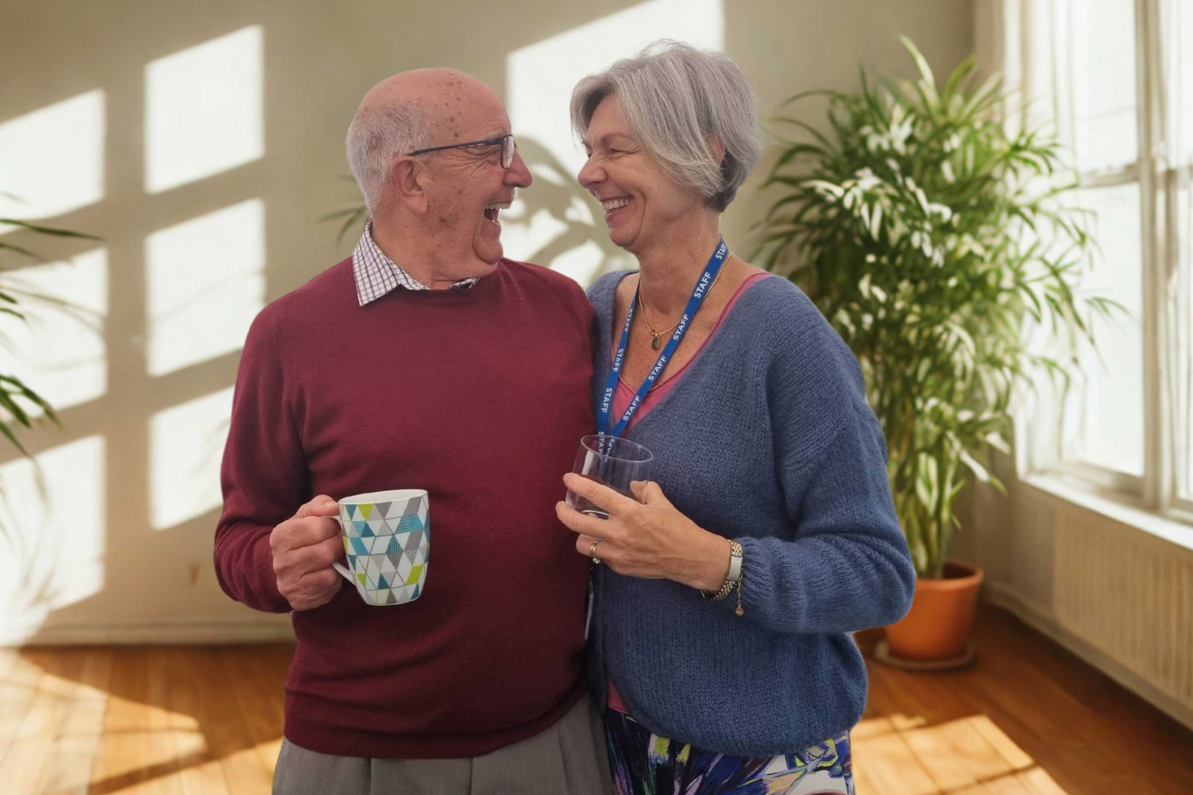 Adult carer with arm around Carers' Centre staff member looking at each other laughing 