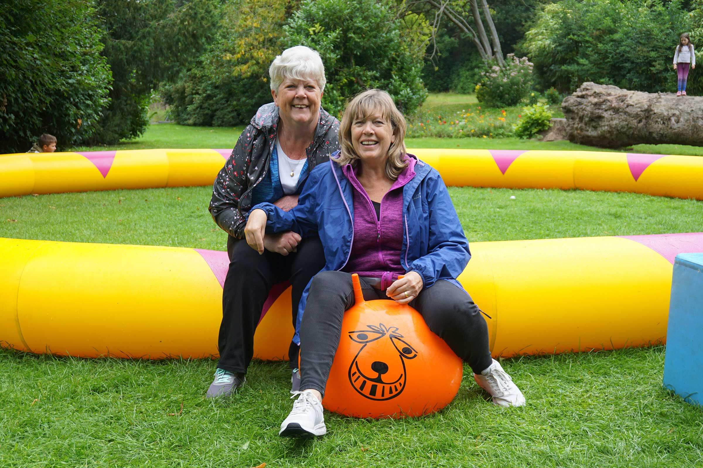 Two ladies, one on a space hopper smiling at the camera