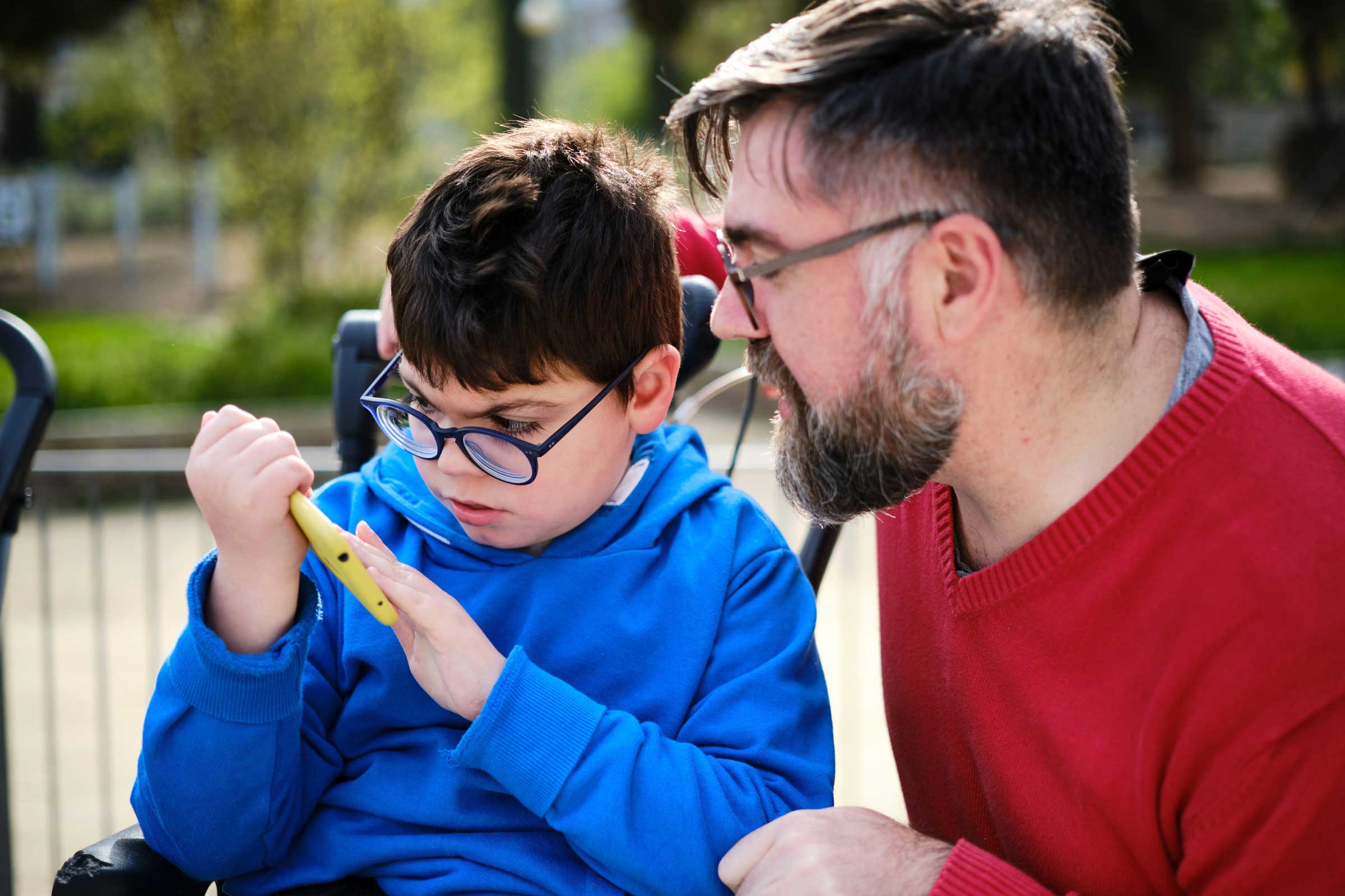 Disabled child looking at a toy with a man next to him watching
