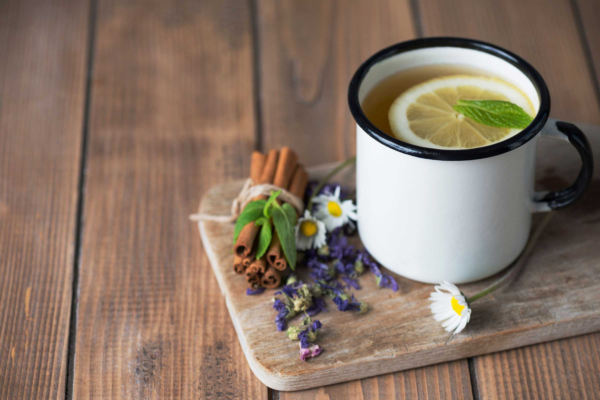 Mug of lemon on a board with flowers and cinnamon
