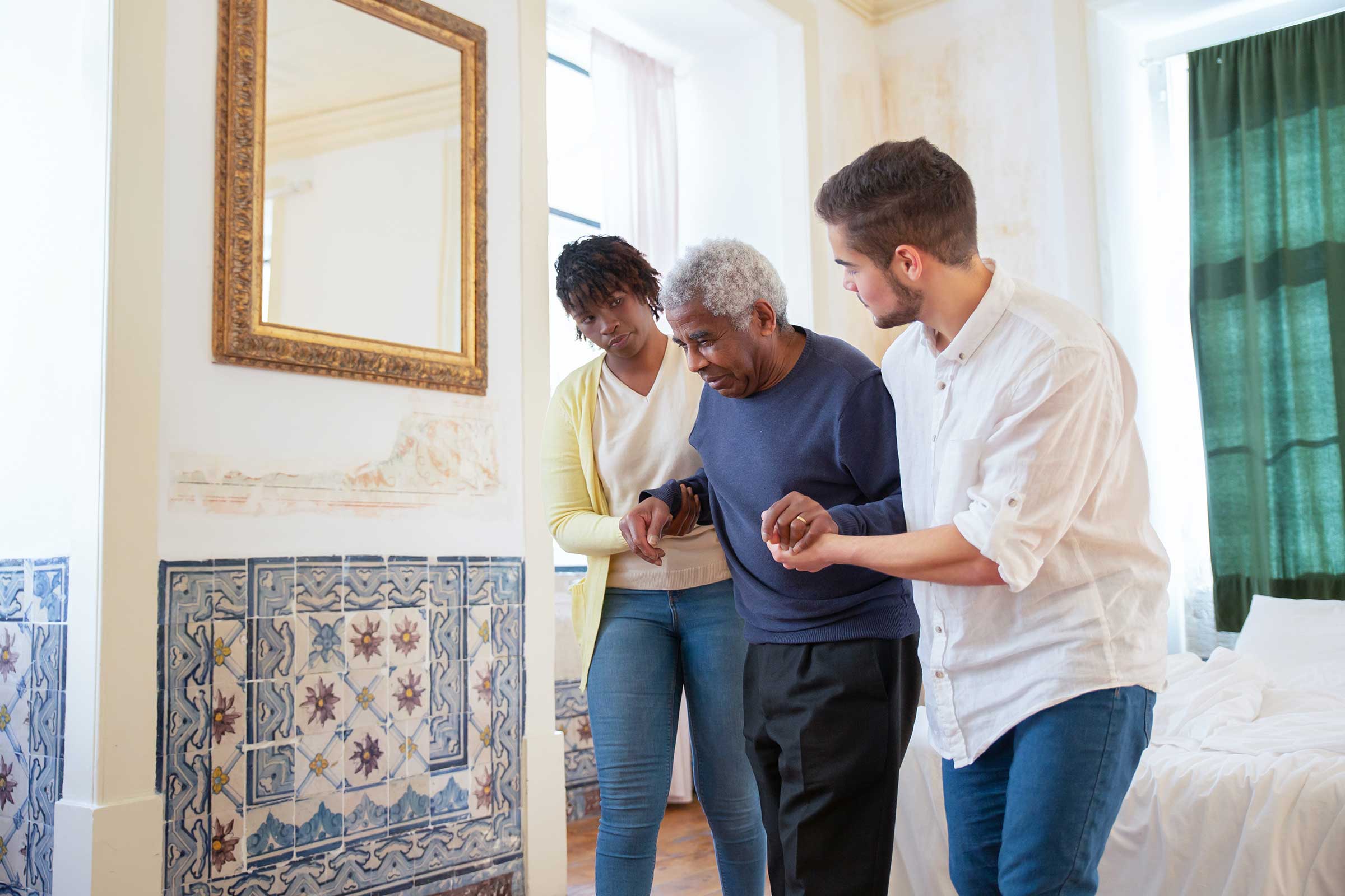 Man and women helping an old man to walk by holding his hands
