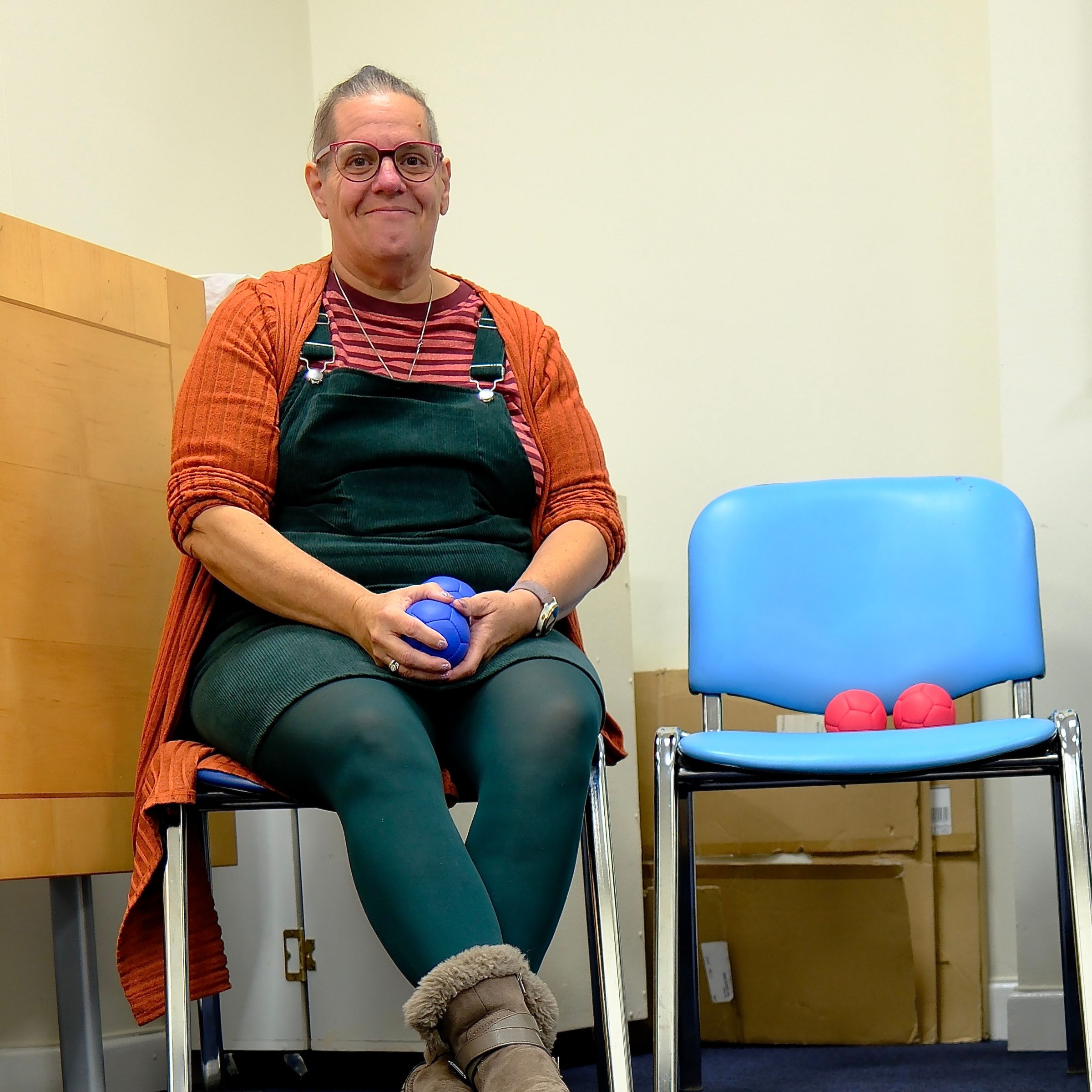 Charlotte wears an orange jumper holding some blue boules