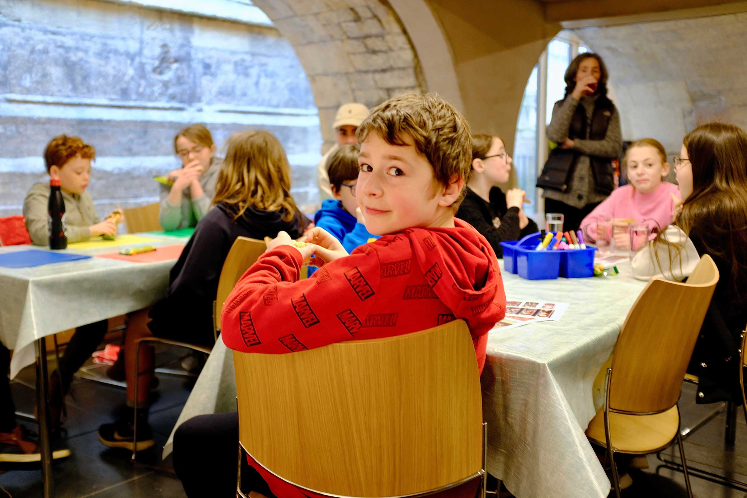 Young person sat at a table looking over his shoulder at the camera