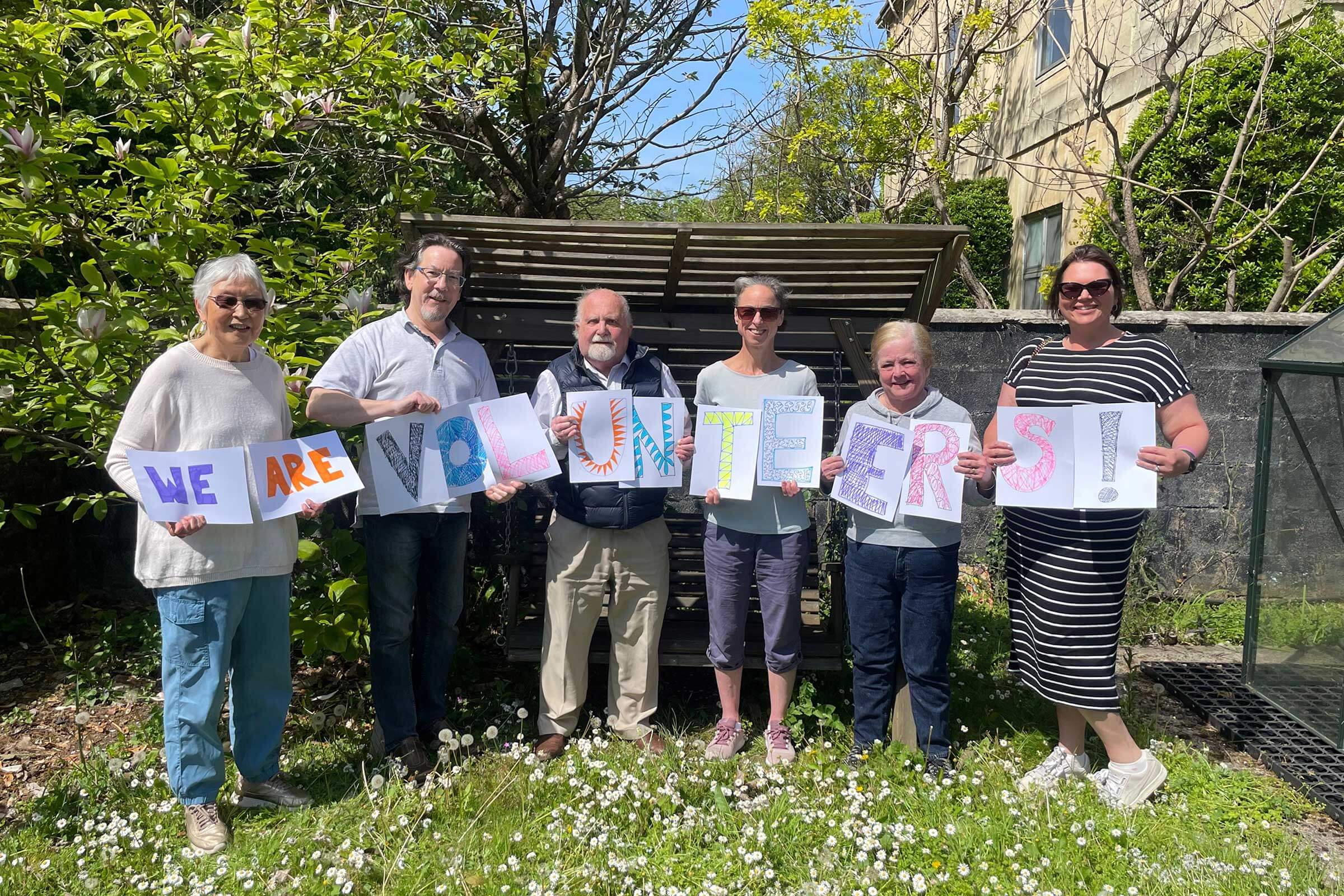 Volunteers holding a sign saying 'We are volunteers!'